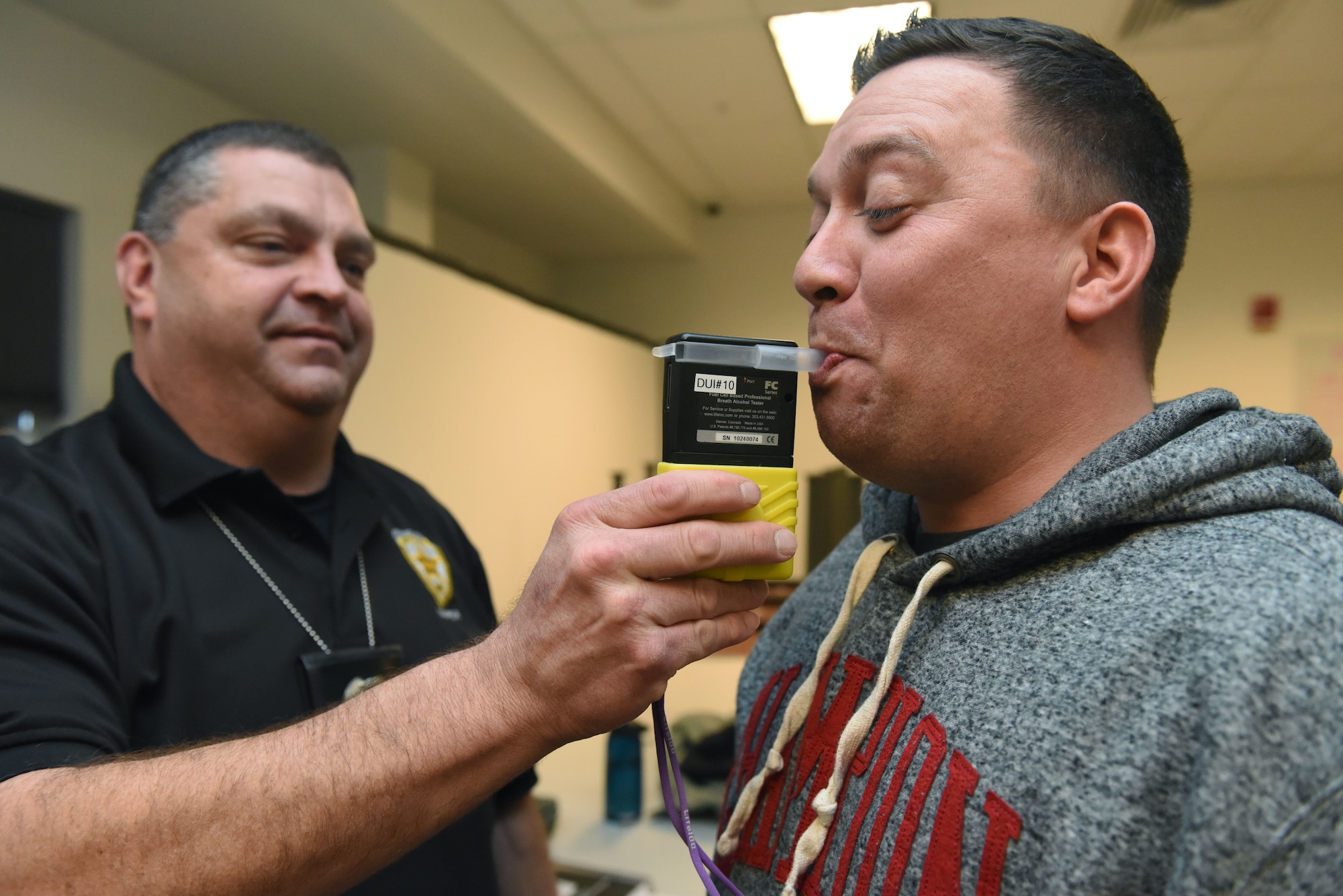 Officer Javen Owens, Aurora Police Department Traffic Unit, uses a breathalyzer to test the blood alcohol content of Master Sgt. Rodney Franken, National Reconnaissance Office/Detachment 3 Security Operations superintendent, during a Standardized Field Sobriety Training, Feb. 12, 2018, on Buckley Air Force Base. Breathalyzers were used before administering the sobriety tests to show just how impaired each individual would be in a driving situation. (U.S Air Force photo by Senior Airman AJ Duprey)