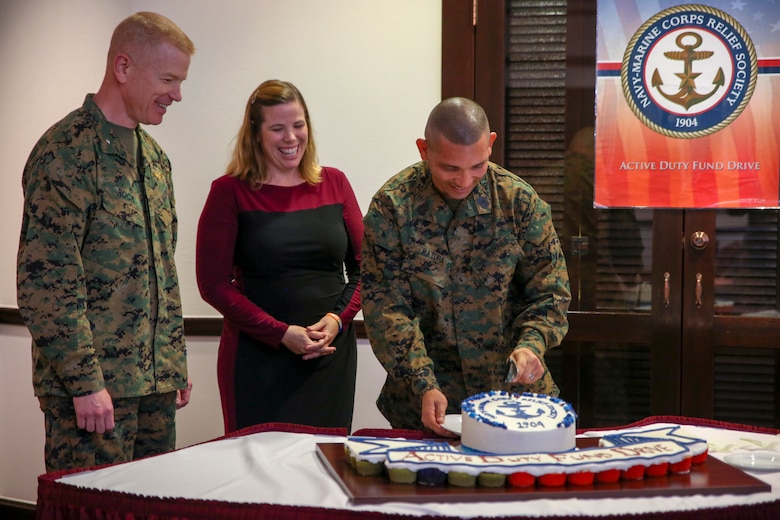 Brig. Gen. Paul Rock Jr., left, Elizabeth Moore, center, and Master Sgt. Aaron Matura cuts the cake during the Navy-Marine Corps Relief Society Active Duty Fund Drive kick off Feb. 27 aboard Camp Foster, Okinawa, Japan. The Active Duty Fund Drive funds programs offered through the NMCRS like the budget for baby classes and providing interest free loans.  Rock is the commanding general of Marine Corps Installations Pacific-Marine Corps Base Camp Butler, Japan. Moore is the director of the Navy-Marine Corps Relief Society, Okinawa. Matura is the coordinator for the Active Duty Fund Drive. (U.S. Marine Corps photo by Pfc. Nicole Rogge)