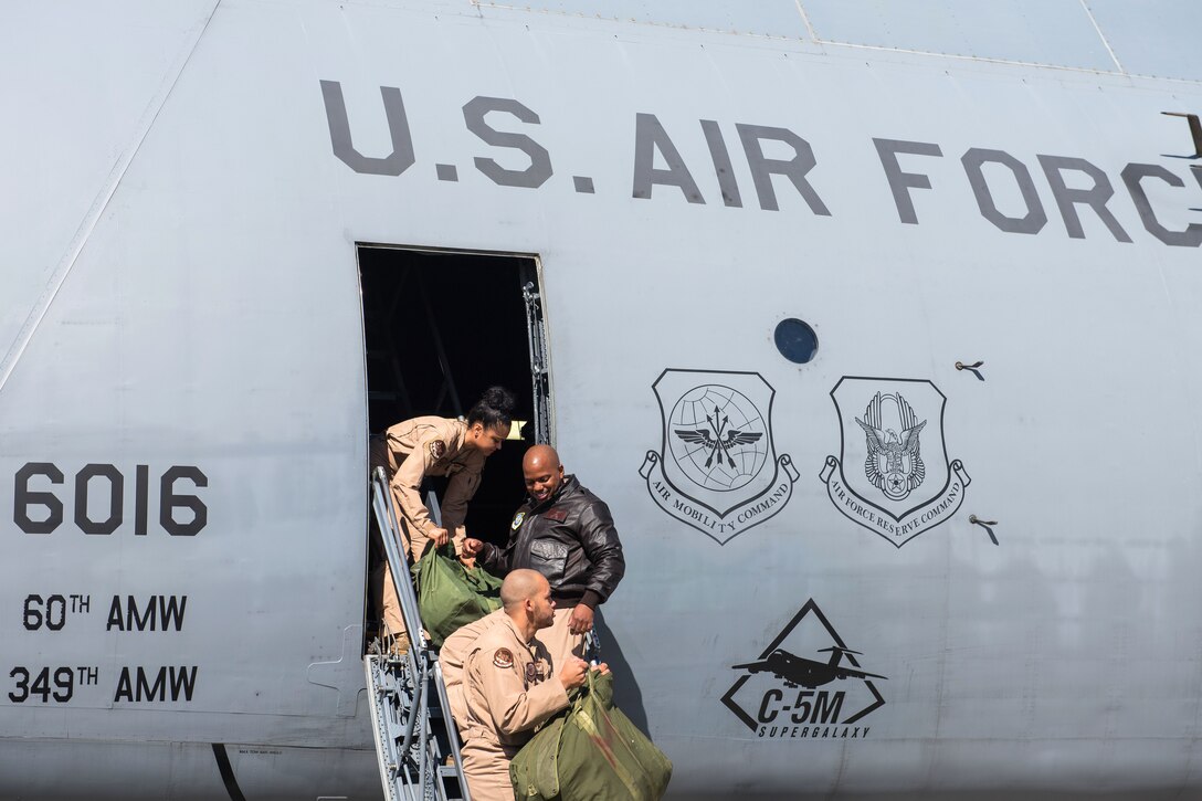 Airmen load bags onto a C-5M Super Galaxy aircraft.