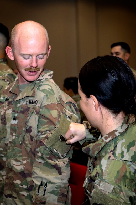 Spc. Meghan O’Connell a member of the Massachusetts National Guard’s 151st Regional Support Group from Scituate, Mass., removes the U.S. Army Central Command patch from Sgt. Matthew Moore, with the Kansas National Guard’s 635th Regional Support Command, Kansas February 28. The two were participating in a change of authority ceremony where the 151st replaced the 635th, beginning only the second ever rotation of National Guard Soldiers to take on the support mission for U.S. Army Central, which commands the U.S.  Army’s land forces in the Middle East.