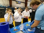 IMAGE: FREDERICKSBURG, Va. - Navy engineer Josh Taylor conducts a liquid nitrogen demonstration with students at the science, technology, engineering and mathematics (STEM) Summit hosted by the Fredericksburg Academy, Feb. 24. Taylor - a Naval Surface Warfare Center Dahlgren Division (NSWCDD) STEM mentor - and the students discussed the Ideal Gas Law, and how it relates different attributes of a fluid. In the picture, they are exposing the inflated balloons to liquid nitrogen and observing that the volume of air inside the balloons decreased as the temperature decreased. Taylor and the students then discussed and demonstrated how changes in temperature could be used to produce kinetic energy, and how temperature changes could affect the behavior of materials. For example, they made flowers shatter like glass, tennis balls that would not bounce, and rubber bands that cracked. 
    "I really enjoyed talking to students and answering their questions, not just about basic principles, but introducing concepts that one doesn't normally explore until college," said Taylor. "I think Dahlgren mentors play a crucial part at venues like this because we help students make a connection between ideas they learn in school and real work they could do one day. Personally, I've met many students who were inspired by events like this to engage the sciences and applied sciences not just as homework - but as a vocation."