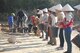 Lao workers assist U.S. service members by lining up with buckets to move dirt to screening stations, where they examined it to locate any belongings and remains of Airmen missing in action since the Vietnam War.