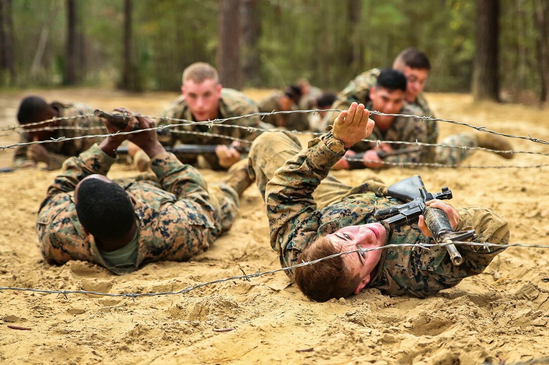 Marines crawl under a barbed wire obstacle during a combat endurance course.