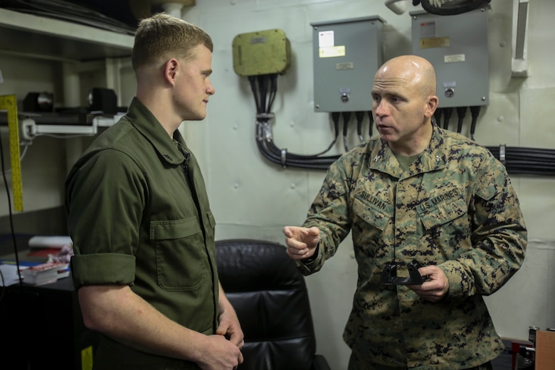 Col. Farrell J. Sullivan, commanding officer of the 26th Marine Expeditionary Unit, asks Cpl. Christopher Bigham, a machinist with the Combat Logistics Battalion 26, 26th Marine Expeditionary Unit a question about the 3D printer aboard the amphibious assault ship USS Iwo Jima (LHD 7) in the Atlantic Ocean, Feb. 26, 2018.