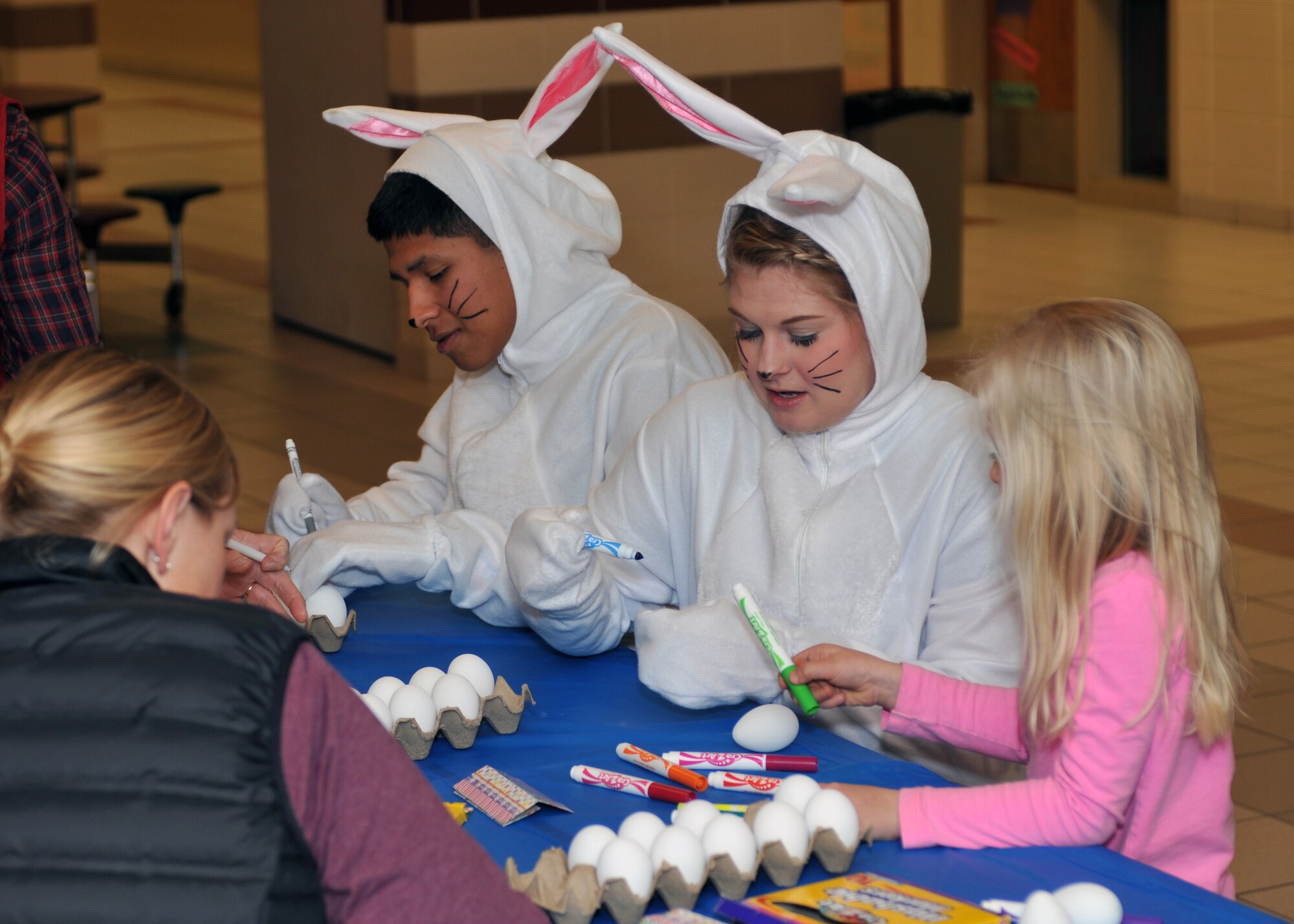 AB Eric Jeronimo and SSgt. Jessie Motley, 185 Air Refueling Wing, Force Support Squadron, Sioux City, Iowa, sport bunny costumes while helping the younger children color Easter eggs at the Spring Fling, at the Sergeant Bluff middle school on Saturday, 3 March, 2018.  The Spring Fling is a morale building event hosted by the 185th ARW Bats Family Club.  (U.S. Air National Guard photo by Master Sgt. Bill Wiseman/Released)