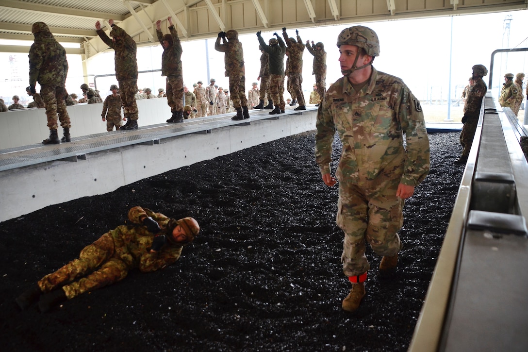 A jumpmaster observes U.S. and Italian soldiers conducting parachute landing fall training.