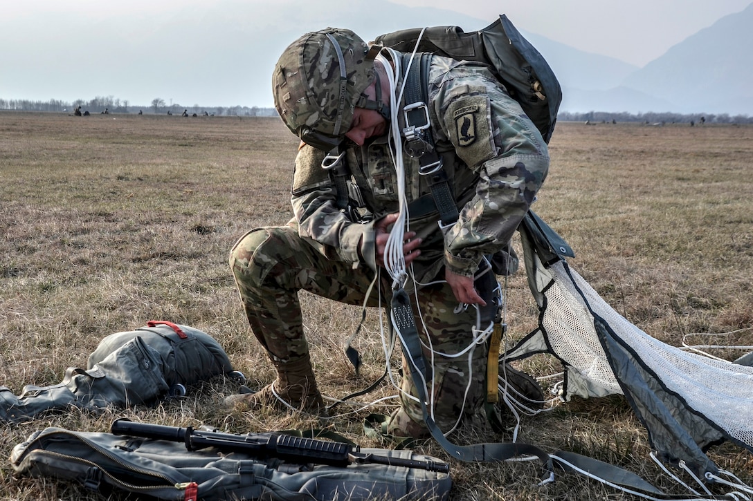 A paratrooper recovers his chute and gear after an airborne operation.