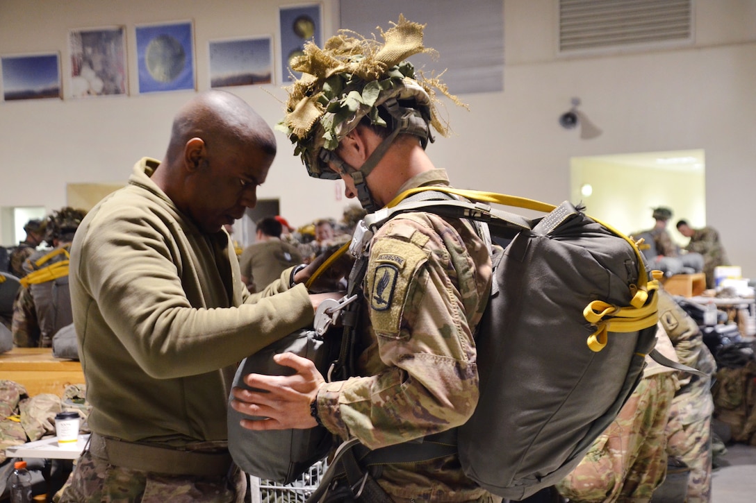 A jumpmaster inspects a soldier’s parachute rig.