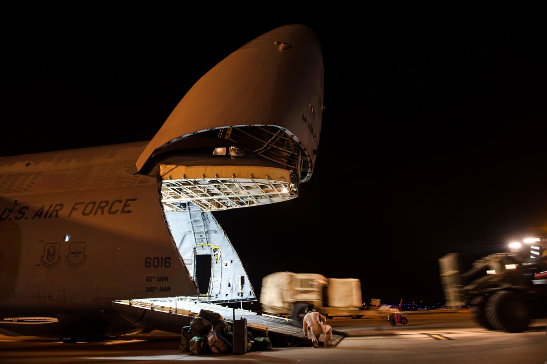 An airman helps load cargo onto a C-5M Super Galaxy aircraft.
