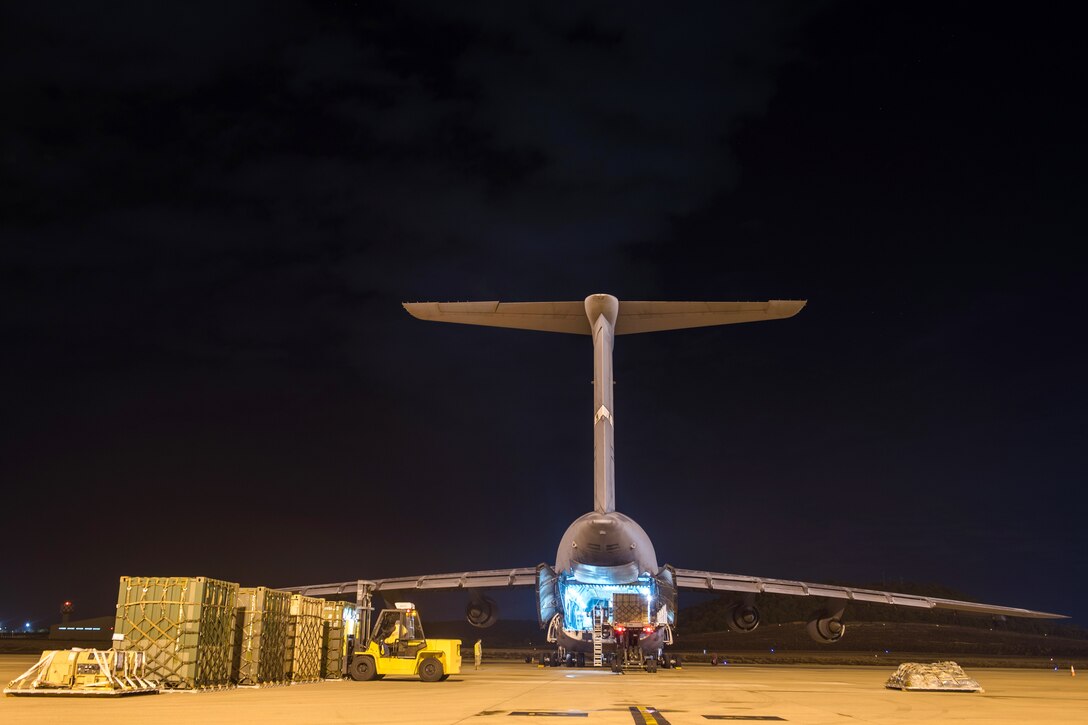 Airmen load cargo onto a C-5M Super Galaxy aircraft.