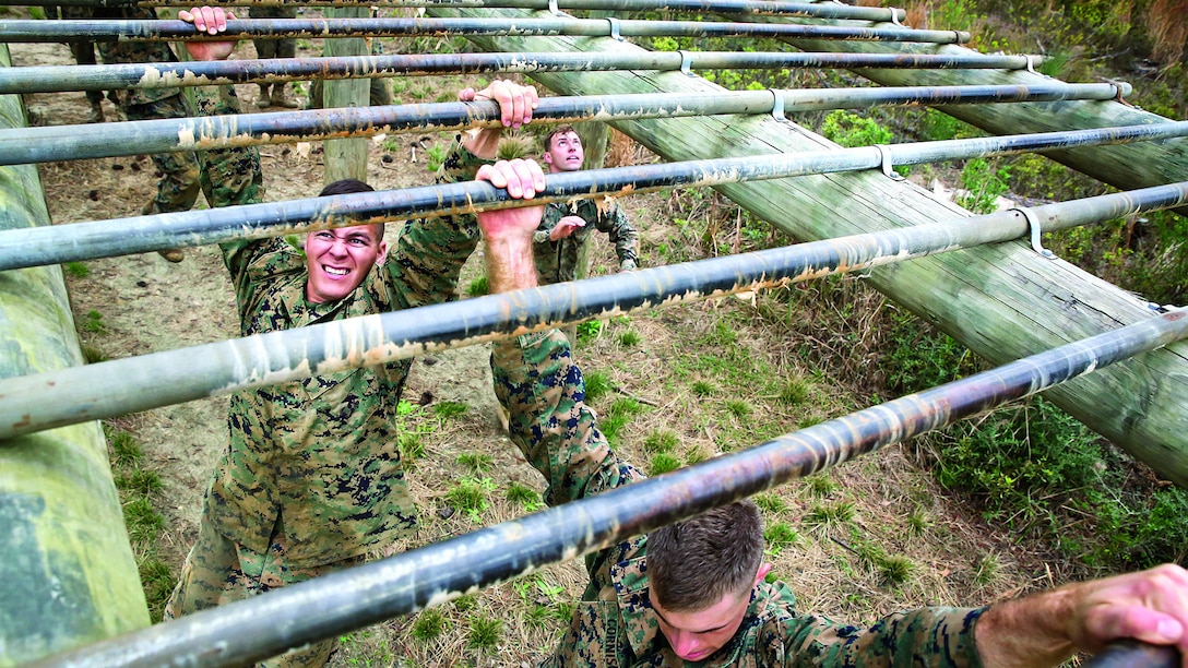 Marines work their way across bars of an obstacle.