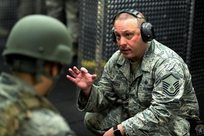 A airman speaks to a service member wearing a helmet during weapons training.