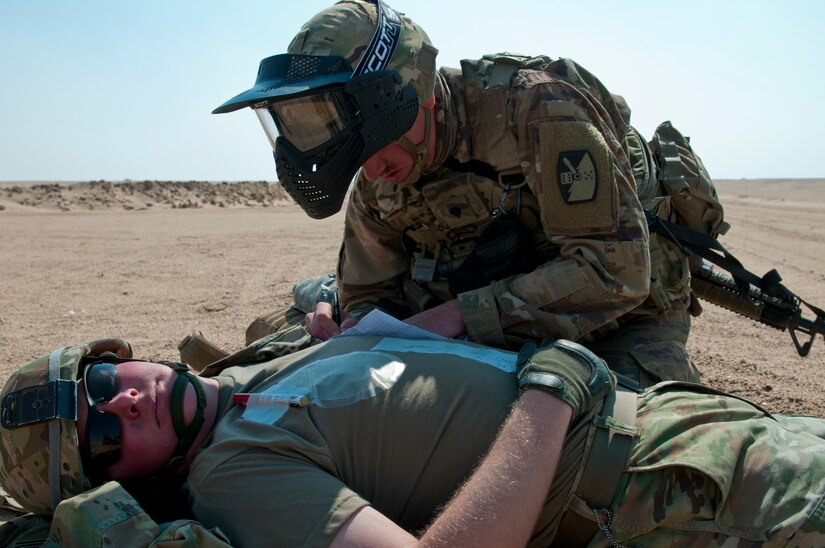 An Army combat lifesaver from Delta Battery, 1st Battalion, 145th Field Artillery Regiment, Utah National Guard, fills out a casualty card for a simulated patient during training on Gerber Training Area, Udairi Range Complex, Kuwait, Feb. 26, 2018. The exercise culminated in a simulated medical evacuation with a UH-60 Black Hawk air ambulance but also included an IED lane and opposing forces role players.