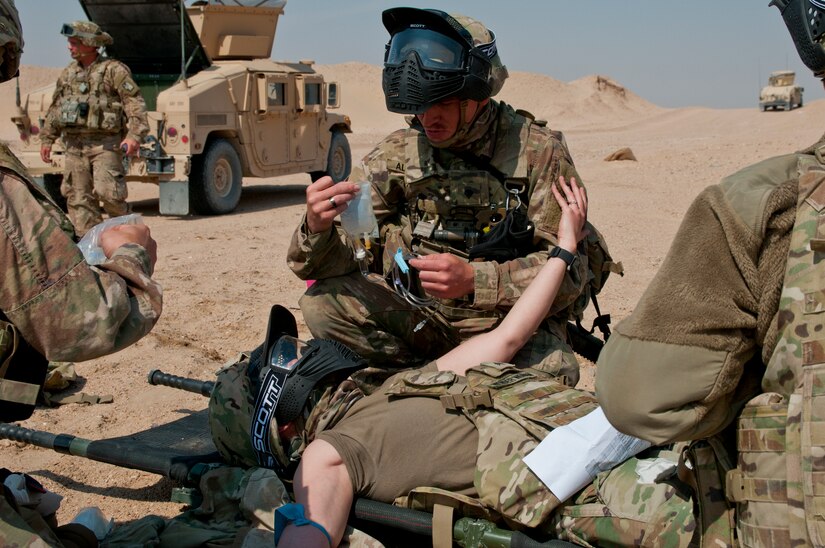 Sergeant Natasia White, a truck driver and simulated casualty, reaches to an Army combat lifesaver-trained Soldier for support as another Soldier prepares to give her a saline lock during training on Gerber Training Area, Udairi Range Complex, Kuwait, Feb. 26, 2018. The exercise culminated in a simulated medical evacuation with a UH-60 Black Hawk air ambulance and also featured an IED lane and opposing forces role players.