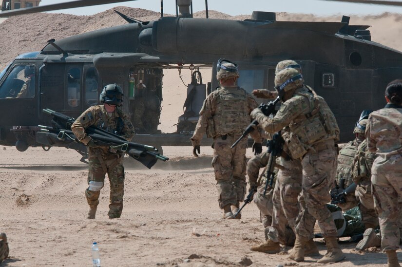 A flight medic approaches Soldiers from Delta Battery, 1st Battalion, 145th Field Artillery Regiment, Utah National Guard, to pick up simulated casualties during training on Gerber Training Area, Udairi Range Complex, Kuwait, Feb. 26, 2018. The exercise included an IED lane and enemy fire in a hostile village before culminating in the simulated medical evacuation with a UH-60 Black Hawk air ambulance.