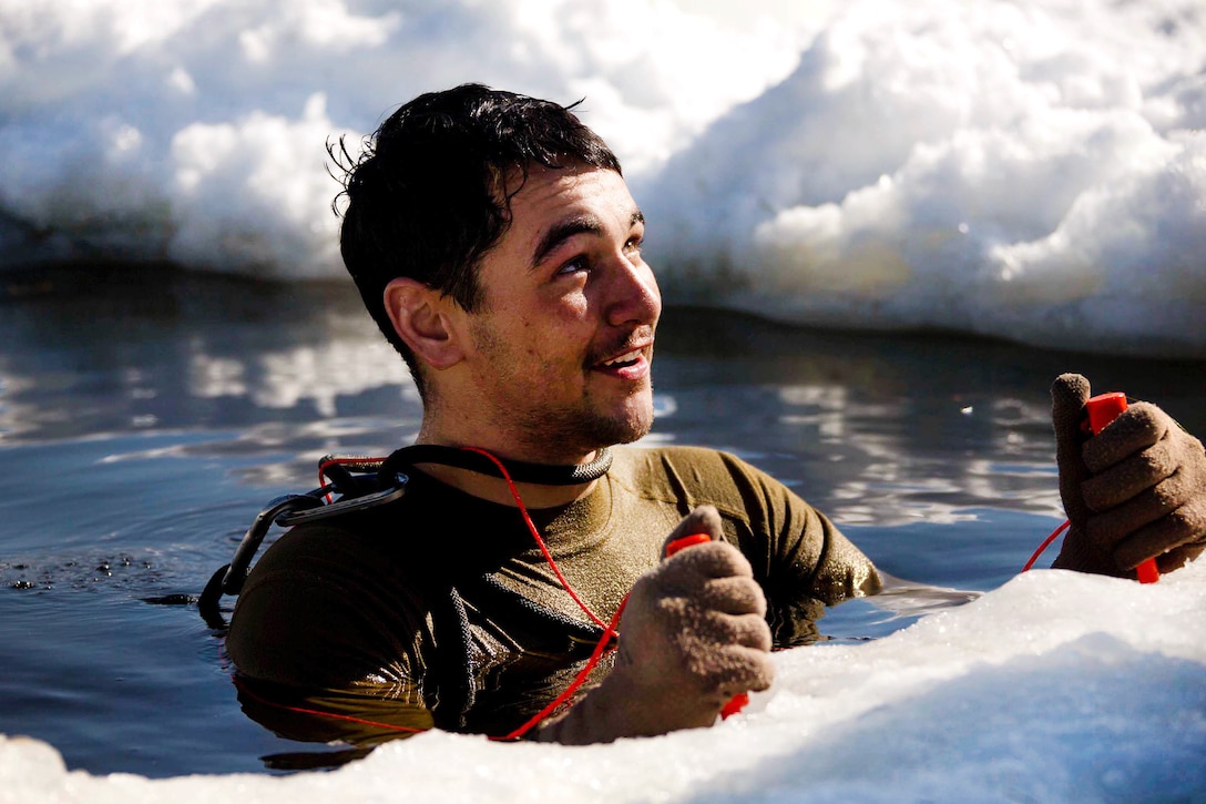 Cpl. Gabriel Strehl stands in freezing water while talking to an instructor as part of cold-water immersion training.