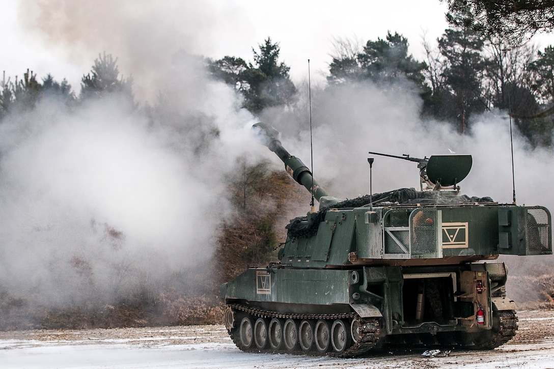 A self-propelled howitzer fires rounds at a simulated enemy target.