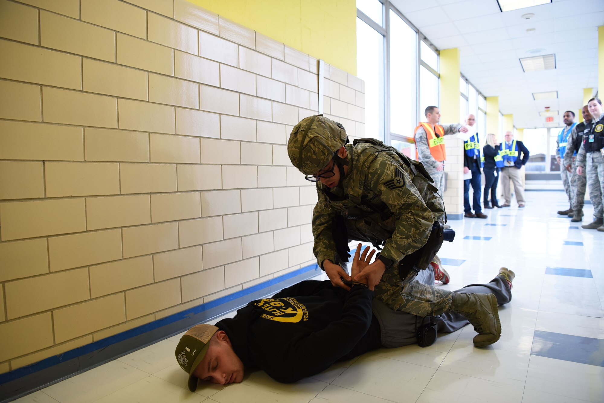 Staff Sgt. Bernard Pecoraro, 436th Security Forces Squadron military working dog handler, is handcuffed by Staff Sgt. Samuel Cruz-Santiago, 436th SFS defender, during the semi-annual active shooter exercise Feb. 26, 2018, at the George S. Welch Elementary School and Dover Air Force Base Middle School on Dover AFB, Del. Members of the 436th Airlift Wing Inspector General team, 436th SFS and the school district spent three months preparing for the actual training day. (U.S. Air Force photo by Airman 1st Class Zoe M. Wockenfuss)