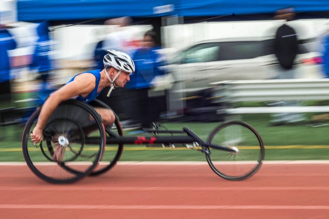A person in a wheel chair races down a track.