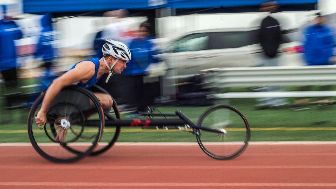 A person in a wheel chair races down a track.