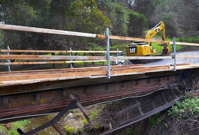 Heavy steel plates are laid across beams of a bridge in order to get heavy machinery across and remove debris from the property. (U.S. Army photo by J. Paul Bruton/Released)