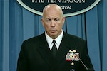 A sailor briefs reporters from behind a podium.