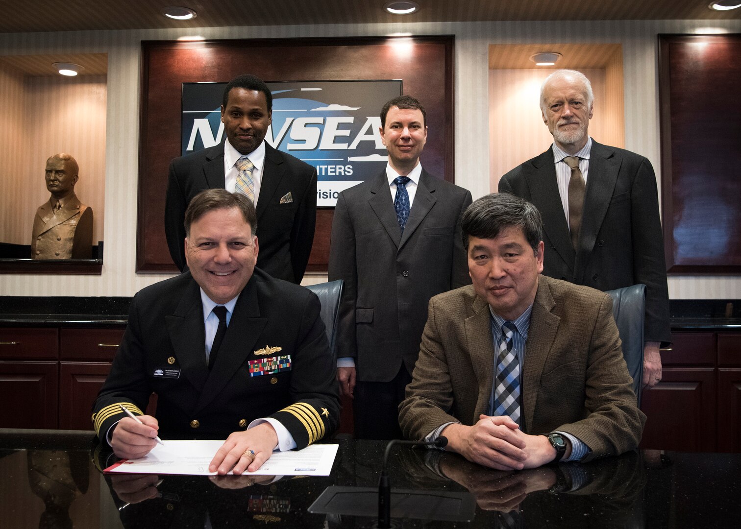 Naval Surface Warfare Center, Carderock Division Commanding Officer Capt. Mark Vandroff (left) signs an Education Partnership Agreement with the University of Iowa on Feb. 26, 2018. With its educational emphasis on naval hydrodynamics and associated technologies, the University of Iowa's partnership will seek to aid in the educational experience of students by providing staff experience and unique facilities and equipment available through Carderock. Carderock's contribution will help to encourage student interest in science, technology, engineering and mathematics. Seated next to Vandroff is Dr. Paul Shang, acting technical director for Carderock. Back row, from left is Dave Ghatt, a patent attorney in Carderock's Office of Counsel; Dr. Thad Michael, a naval architect with Carderock's Propulsors Branch; and Dr. John Barkyoumb, Carderock's director of strategic relations.