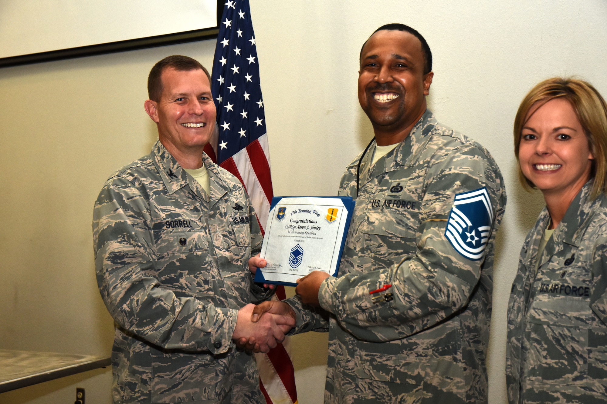 U.S. Air Force Col. Jeffrey Sorrell, 17th Training Wing vice commander, presents Master Sgt. Aaron Shirley, 315th Training Squadron instructor, a promotion certificate with Chief Master Sgt. Bobbie Reinsche, 17th Training Wing command chief, at the Event Center on Goodfellow Air Force Base, Texas, March 1, 2018. In celebration of individuals being selected for senior master sergeant, a party was held at the Event Center. (U.S. Air Force photo by Airman 1st Class Seraiah Hines/Released)