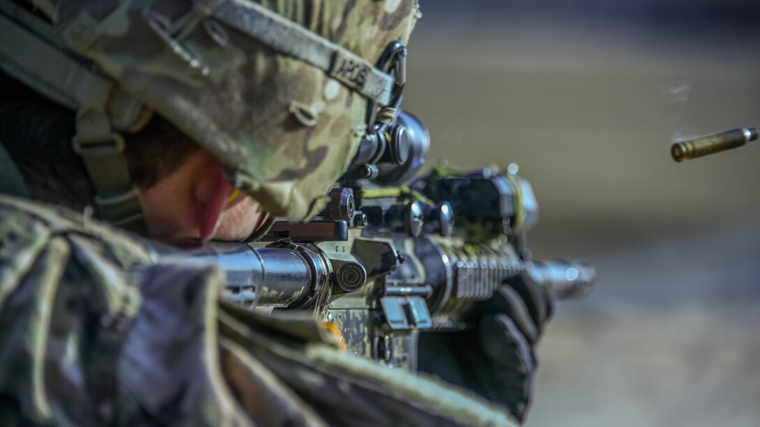 A soldier fires a weapon and a casing flies through the air.