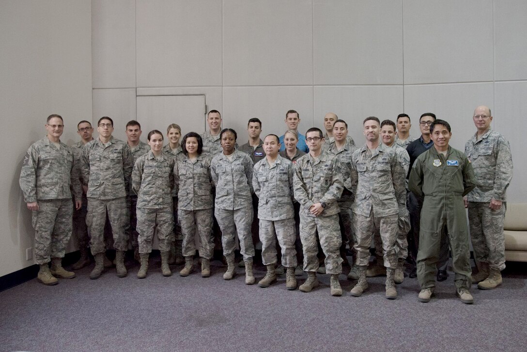 The newest members of the 349th Air Mobility Wing pose for a photo with Col. Raymond Kozak, the 349th AMW commander, far right, and Chief Master Sgt. Bryan Payne, the 349th AMW command chief, far left, during the March Newcomers' brief.