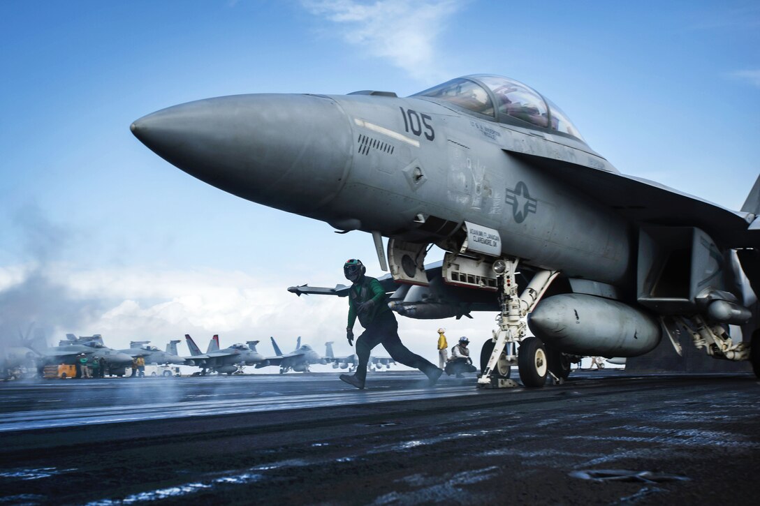 A catapult crewman prepares an F/A-18F Super Hornet aircraft for takeoff.