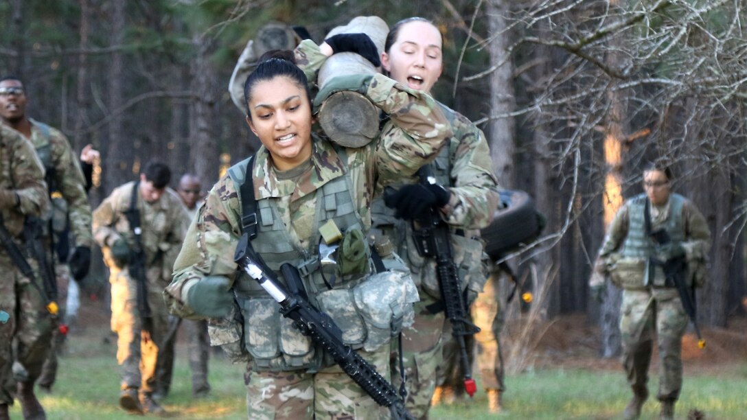 Two soldiers carry a log while running.