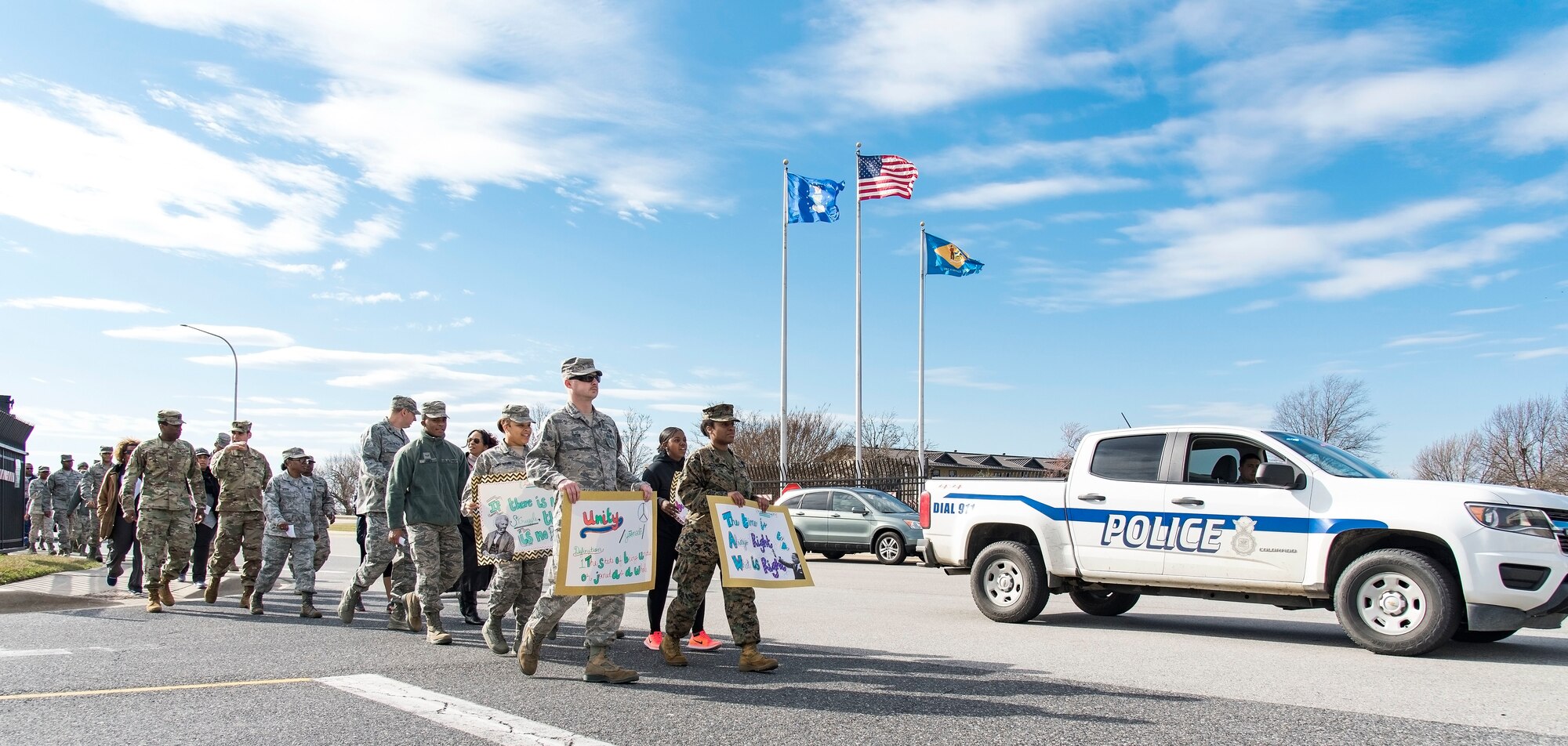 Participants in the Black History Month Unity Walk approach the main gate on their way to the base flag pole Feb. 28, 2018, on Dover Air Force Base, Del. The African-American Heritage Committee sponsored the walk here at Dover AFB and members of the 436th Security Forces Squadron provided escort and traffic control for the walk. (U.S. Air Force photo by Roland Balik)
