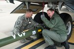 A German airman signals to a tug operator after attaching a tow bar to an Airbus A400M with the help of 167th Airlift Wing maintainer, Master Sgt. David Rinard, at the 167th AW, Feb. 23.
