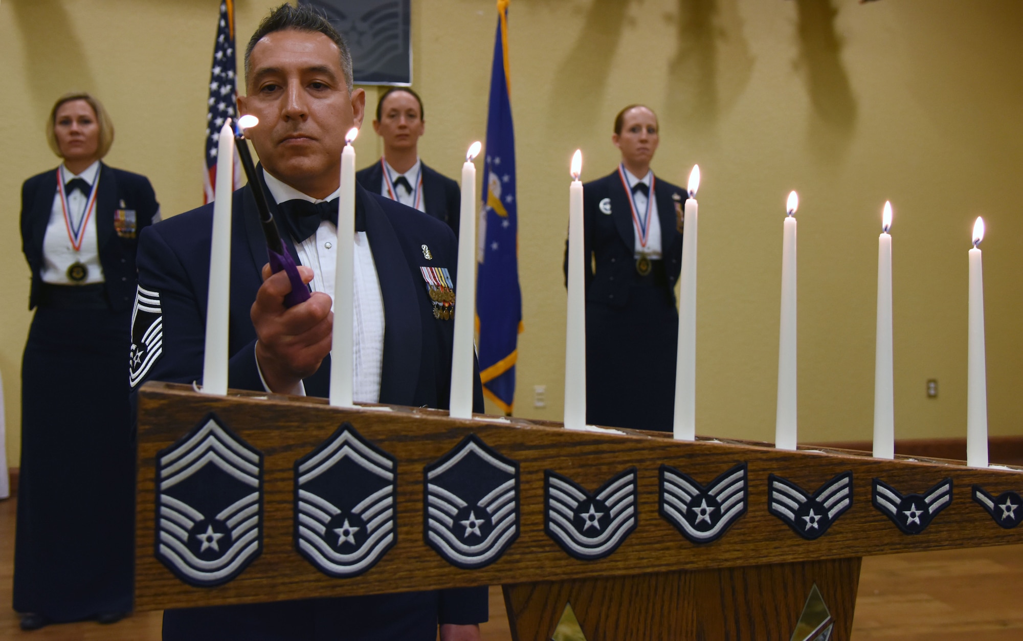 Chief Master Sgt. Claudio Castillo, 81st Surgical Operations Squadron superintendent, lights a candle during a candle lighting ceremony during the Chief Induction Ceremony at the Bay Breeze Event Center March 1, 2018, on Keesler Air Force Base, Mississippi. Three Keesler Airmen earned their chief master sergeant stripe during the 2018 promotion release. (U.S. Air Force photo by Kemberly Groue)