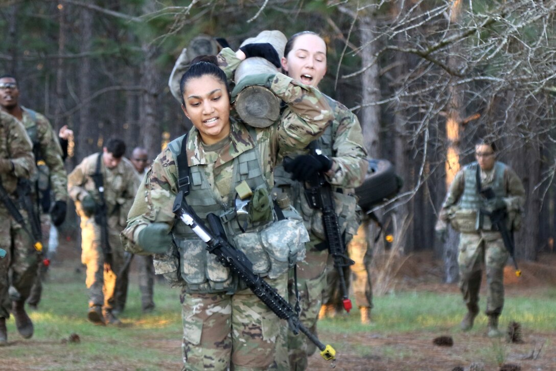 Two soldiers carry a log while running.