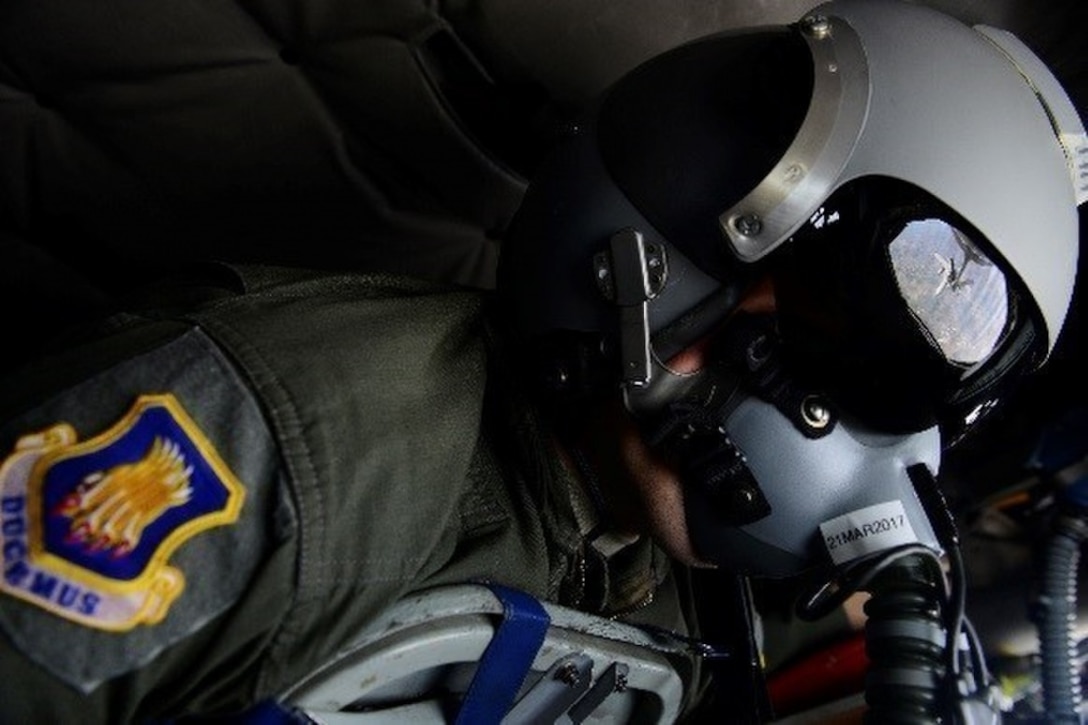 An F-18 Hornet is reflected in the face mask of an airman during a refueling operation.