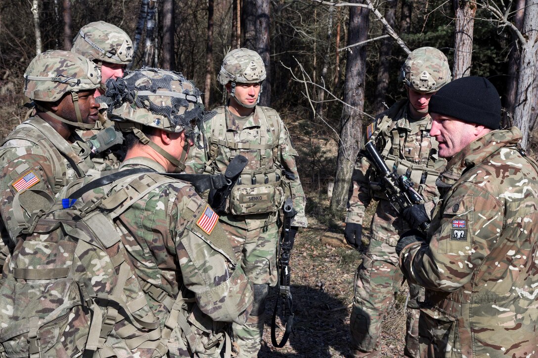 A British soldier briefs U.S. soldiers on their first task.