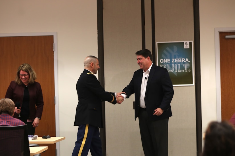 Army Reserve Col. Daniel Jaquint, left, G3 operations chief for the 85th Support Command, shakes the hand of his civilian employer, Joe White, Senior Vice President of Enterprise Mobile Computing at a company quarterly meeting in Long Island, New York, Mar. 1, 2018.