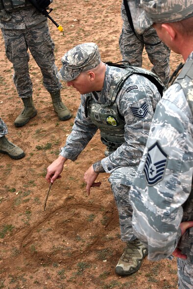 U.S. Air Force Tech. Sgt. Mark Karas, 17th Security Forces Squadron noncommissioned officer in charge of training, draws in the dirt to explain 360 degree security to students of the Warrior Ancillary Specialized Training Program at the mock Forward Operating Base on Goodfellow Air Force Base, Texas, Feb. 28, 2018. The students were required to use the techniques taught into practice during their final training exercise later that day. (U.S. Air Force photo by Airman 1st Class Seraiah Hines/Released)