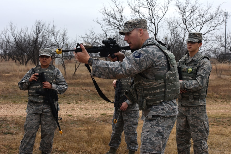 U.S. Air Force Tech Sgt. Mark Karas, 17th Security Forces Squadron noncommissioned officer in charge of training, demonstrates proper handling of a weapon during the bounding portion of exercises during the final training exercise for Warrior Ancillary Specialized Training Program at the mock Forward Operating Base on Goodfellow Air Force Base, Texas, Feb. 28, 2018. The students were taught how to take proper cover, prevent flagging, communication and other skills during the exercise. (U.S. Air Force photo by Airman 1st Class Hines/Released)