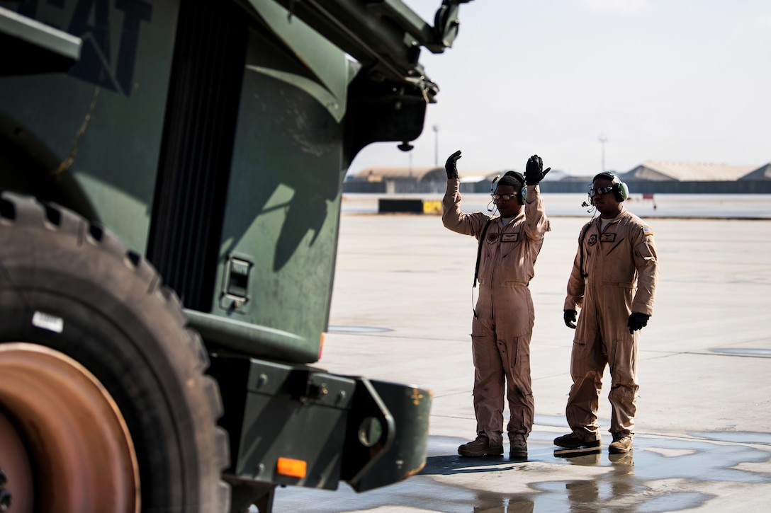 Airman Cameron Young, left, guides a forklift off a C-5M Super Galaxy aircraft.