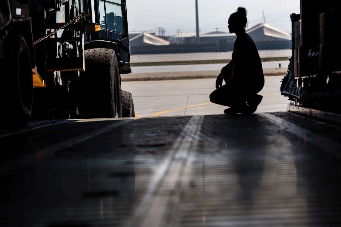 Senior Airman Lauren Foote guides a forklift for clearance offloading cargo.