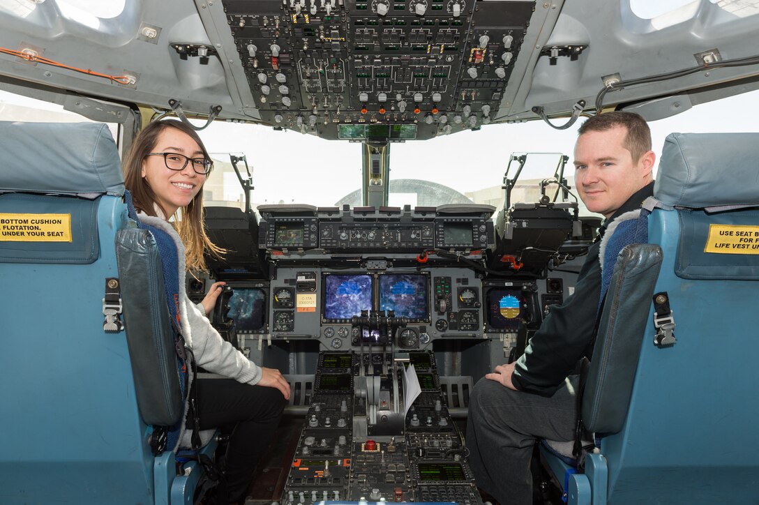 Karen Sanchez, Human Systems Integration engineer, and Matt Osburn, 418th Flight Test Squadron C-17 lead Engineer, sit in the cockpit of a C-17 Globemaster III with new Replacement Head-Up Displays installed for testing. (U.S. Air Force photo by Kyle Larson)