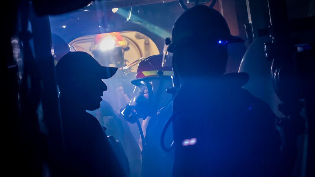 Sailors participate in a general quarters drill inside a guided-missile destroyer.