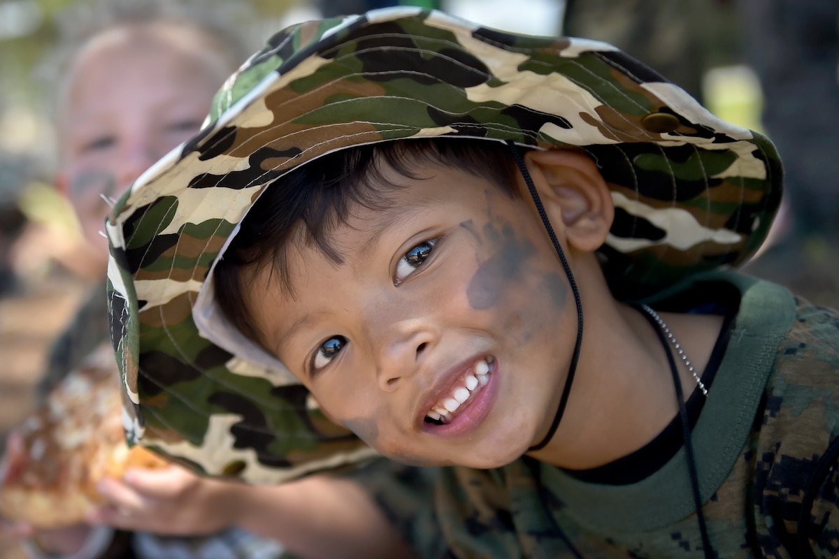 A child wearing a had and face paint poses for a photo.