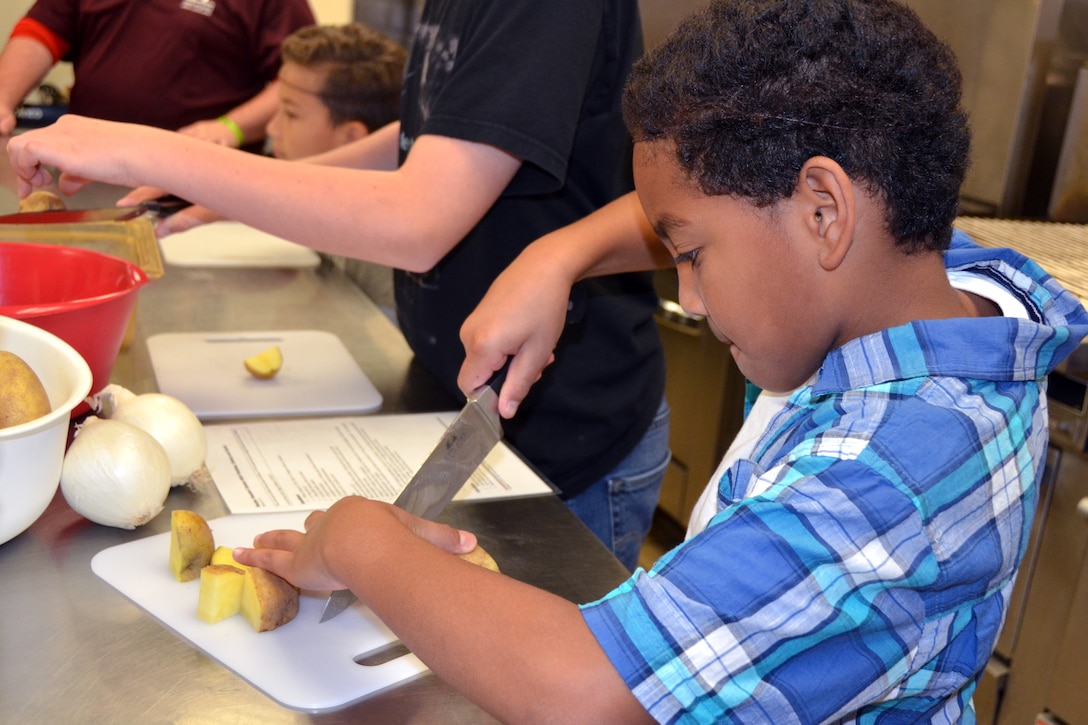 A child cuts potatoes with a knife.
