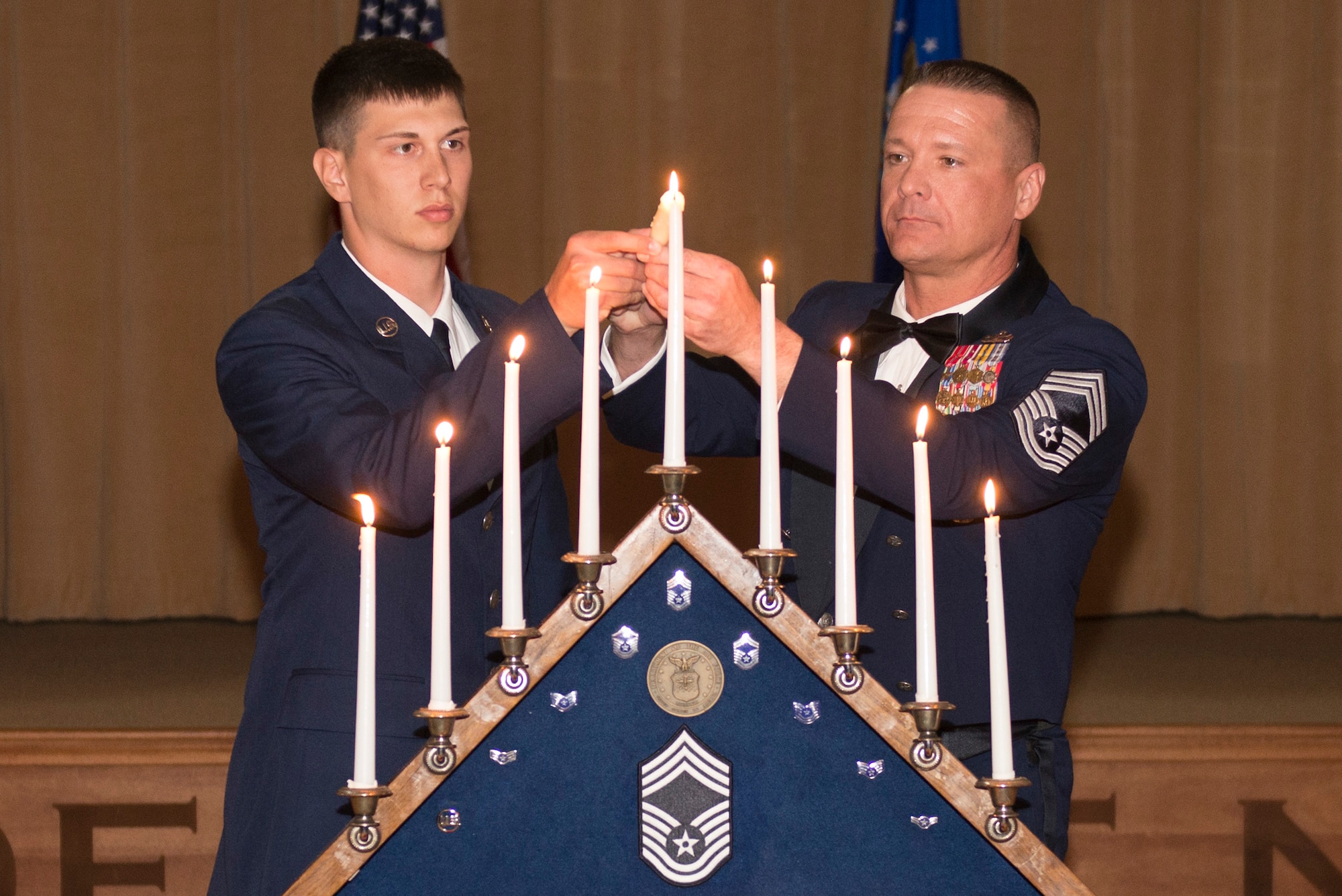 An Airman Basic and a chief master sergeant light the final candle on the ceremonial candelabrum during the Chief Recognition Ceremony at Luke Air Force Base, Ariz., March 3, 2018. The candles represented each of the nine enlisted ranks that an Airman must pass through before reaching chief. (U.S. Air Force photo/Senior Airman Ridge Shan)