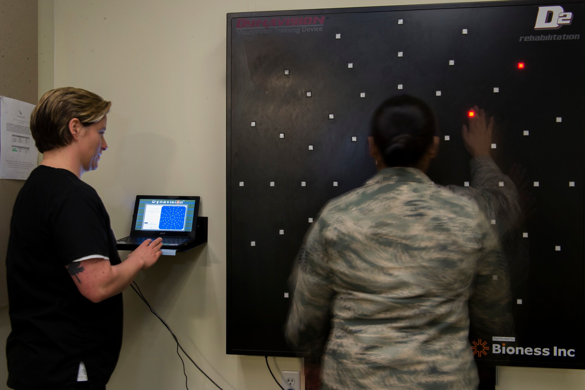 Dr. Deana Kubosh, Traumatic Brain Injury clinic occupational therapist, examines a patient using a Visuomotor training device at Joint Base Elmendorf-Richardson, Alaska, Feb. 26, 2018. This device is used for rehabilitation through the testing of motor and cognitive reaction speeds.