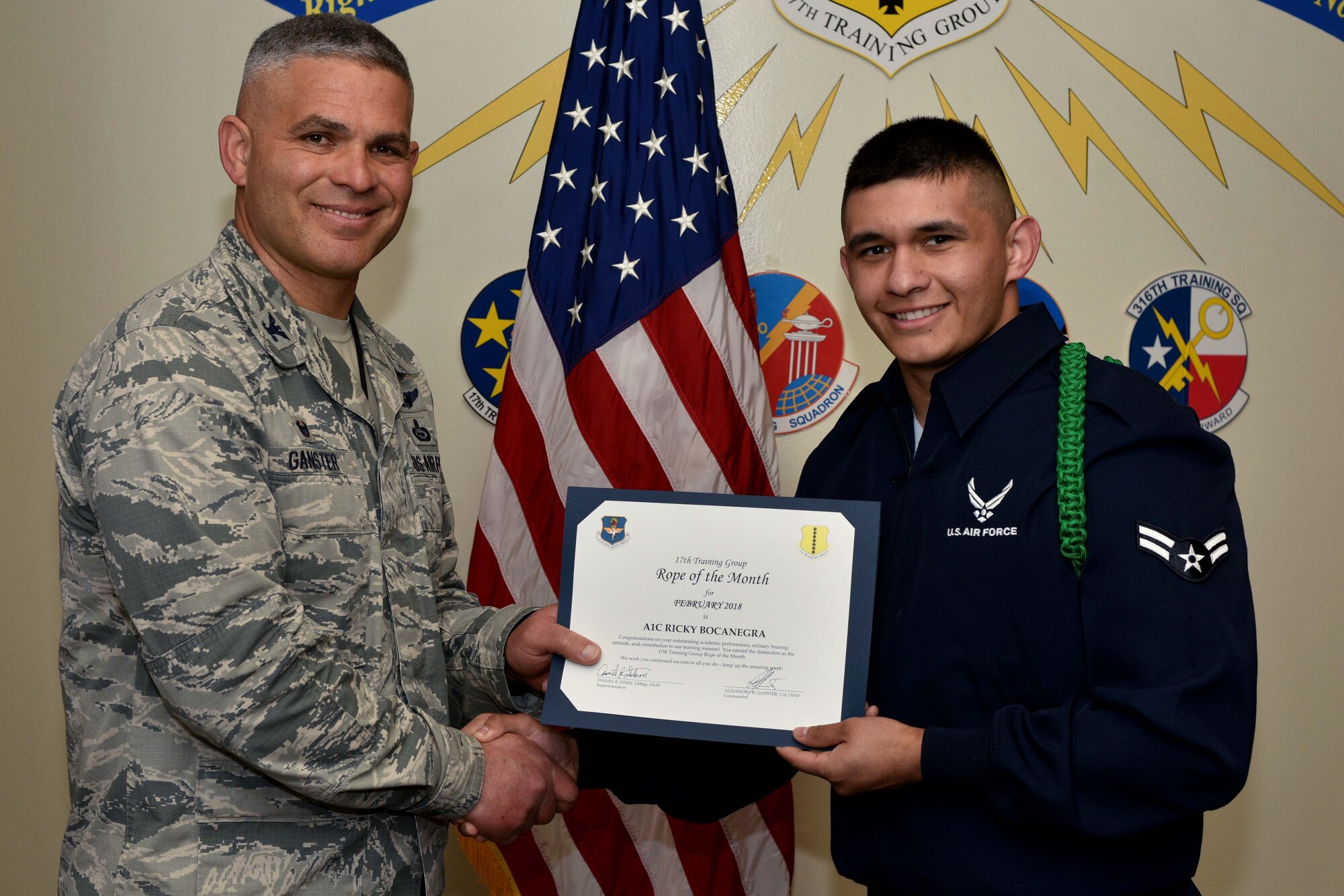 U.S. Air Force Col. Alex Ganster, 17th Training Group commander, presents the 17th TRG Rope of the Month certificate to Airman 1st Class Ricky Bocanegra, 315th Training Squadron trainee, in Brandenburg Hall on Goodfellow Air Force Base, Texas, March 2, 2018.  The mission of the 17th TRG is to train, develop and inspire professional fire protection and intelligence, surveillance and reconnaissance warriors. (U.S. Air Force photo by Senior Airman Randall Moose/Released)